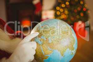 Close up of santa pointing his finger on the globe