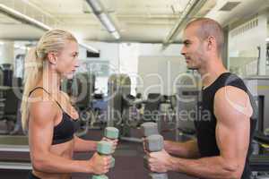 Couple exercising with dumbbells in gym