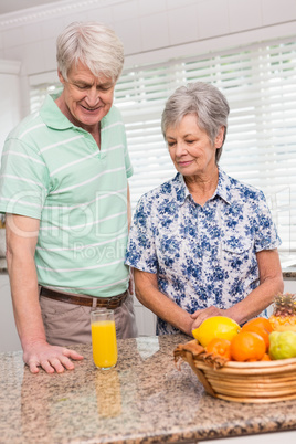 Senior couple looking at glass of orange juice