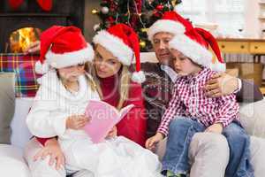 Festive family wearing santa hat while reading on the couch