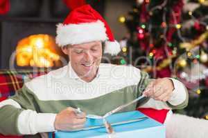 Smiling man in santa hat opening a gift