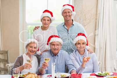 Happy extended family in santa hat toasting at camera Happy extended family in santa hat toasting at camera