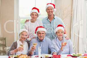 Happy extended family in santa hat toasting at camera