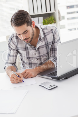 Casual businessman writing at his desk