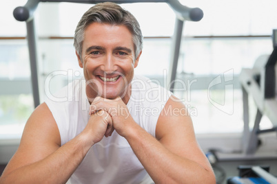 Fit man smiling at camera in fitness studio