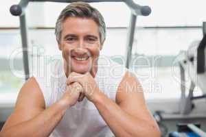 Fit man smiling at camera in fitness studio