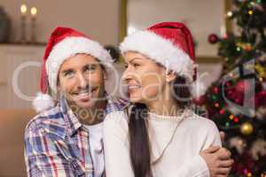 Festive couple in santa hat hugging on the couch