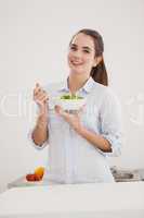 Pretty brunette eating bowl of salad