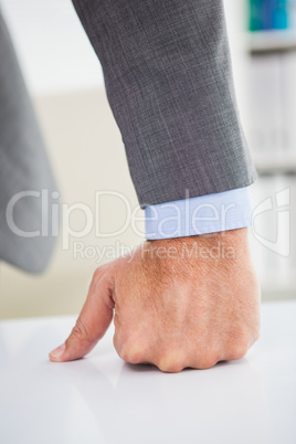 Businessmans fist clenched over desk