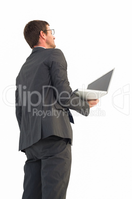 Businessman looking up holding laptop