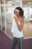 Fit woman drinking water in fitness studio