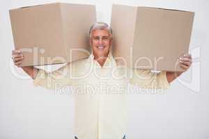 Smiling man balancing heavy cardboard boxes