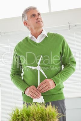 Casual businessman holding model wind turbine