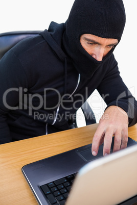 Thief with balaclava hacking a laptop