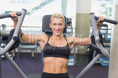 Fit young woman using fitness machine at gym