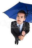 Anxious businessman under umbrella looking up