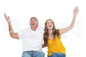 Casual couple smiling with arms raised