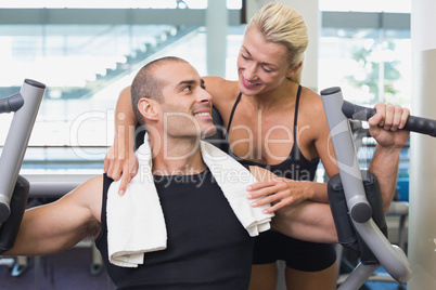 Trainer assisting man on fitness machine at gym