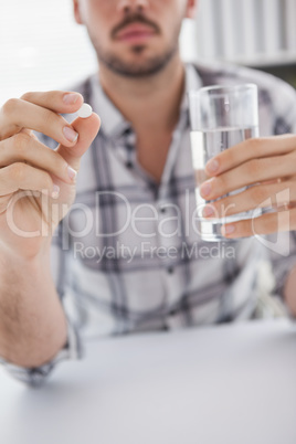 Casual businessman holding glass of water and tablet