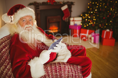 Happy santa using tablet on the couch