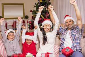 Festive family in santa hat cheering on the couch