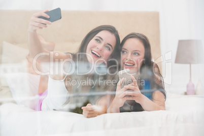 Pretty friends taking a selfie on bed