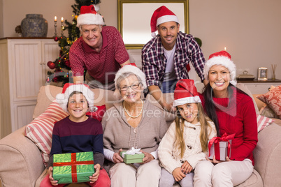 Portrait of a happy extended family in santa hat holding gifts