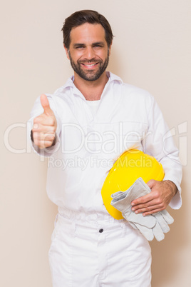 Handyman holding his yellow helmet showing thumbs up