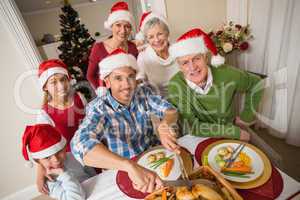 Father in santa hat carving chicken at christmas dinner