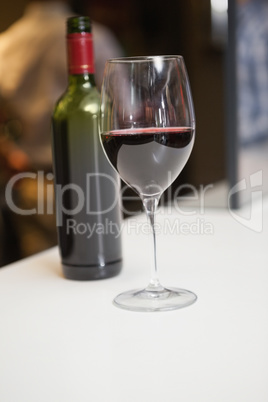 Close up of red wine into glass in front of the bottle