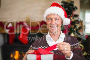 Smiling handsome man in santa hat opening a gift