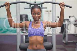 Fit woman using the weights machine for her arms