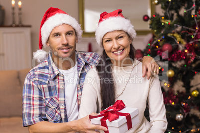 Smiling couple in santa hat holding present