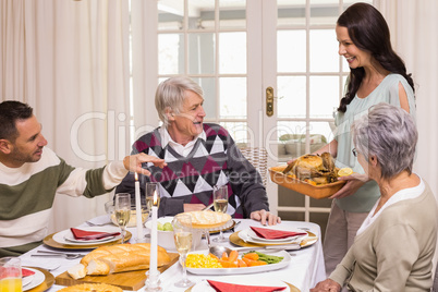 Woman holding turkey roast with family at christmas