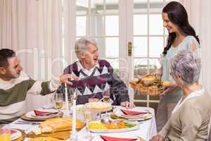 Woman holding turkey roast with family at christmas