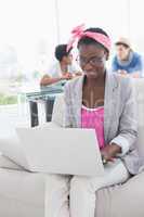 Young creative woman using laptop on couch