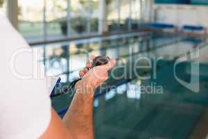 Cropped swimming coach with stopwatch by pool at leisure center