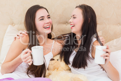Pretty friends having coffee on bed