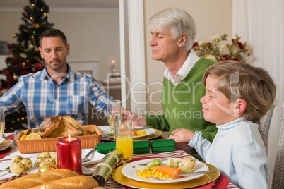 Extended family saying grace before christmas dinne