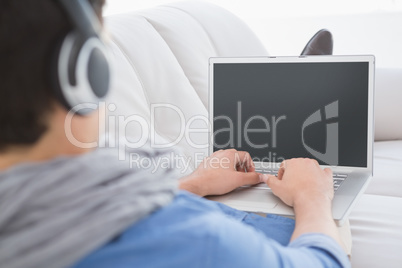 Young creative man using laptop on couch