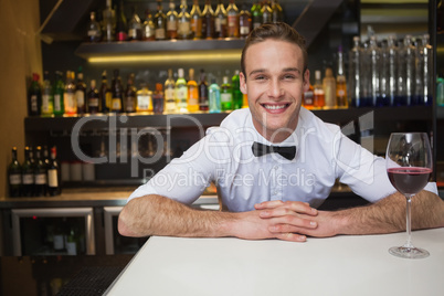 Smiling bartender having glass of red wine