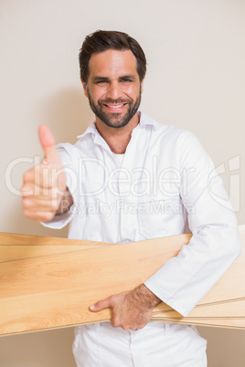 Carpenter holding planks showing thumbs up