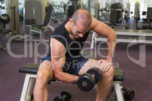 Young man exercising with dumbbell in gym