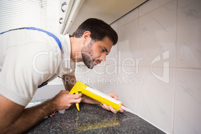 Plumber putting filling in between tiles