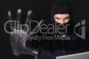 Hacker in balaclava with fingers spread out