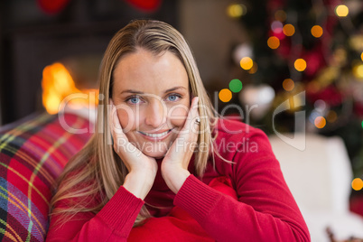 Woman resting her head on her hands is lying on the couch