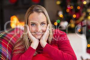 Woman resting her head on her hands is lying on the couch