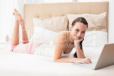 Pretty brunette using laptop on bed