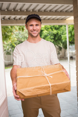 Delivery man smiling at camera offering parcel