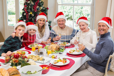 Smiling family in santa hat toasting to camera